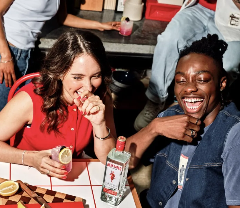 Two people laughing together over drinks at a table
